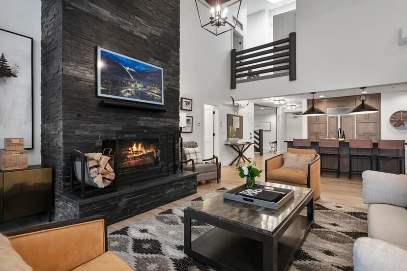 Modern living room with stone fireplace, stylish furniture, and open kitchen design.